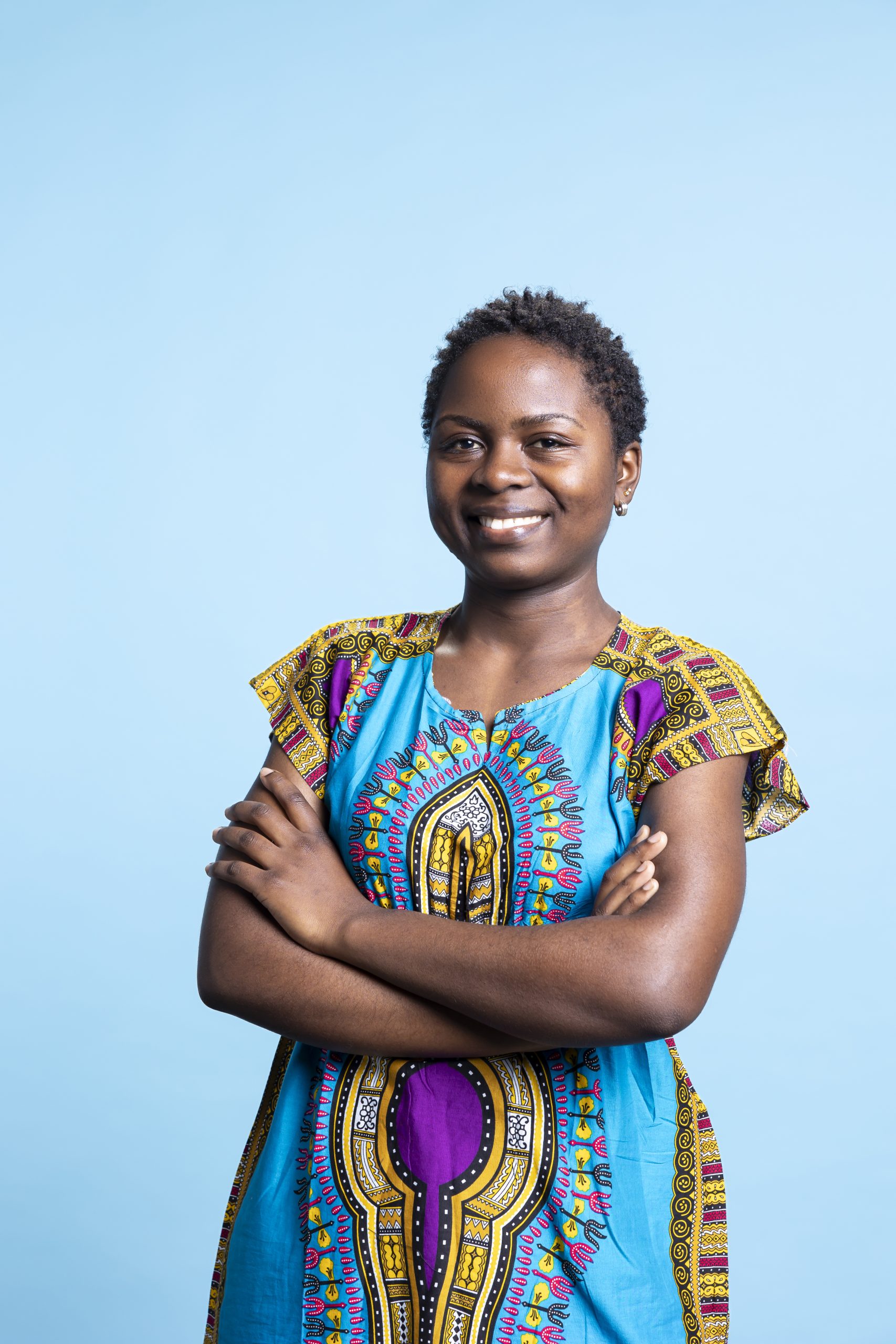 Portrait of cheerful woman standing with arms crossed on camera